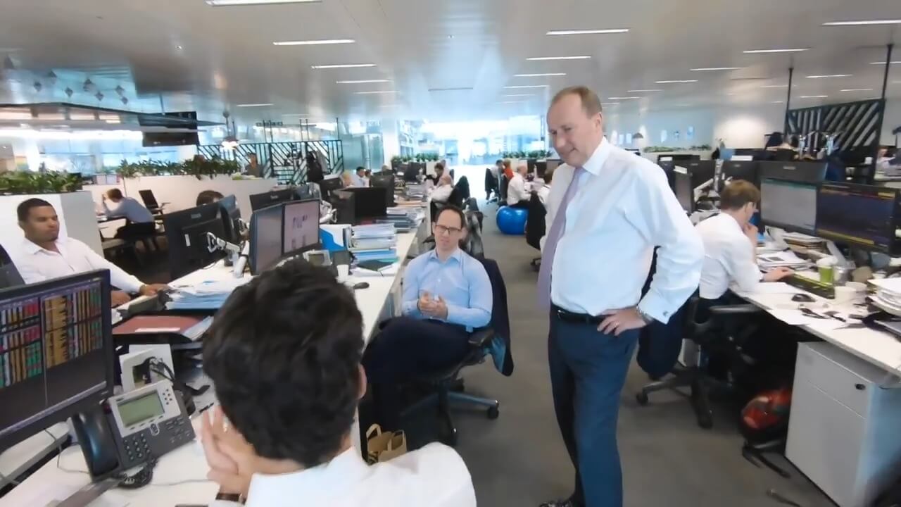 The man is talking to his colleagues in the office